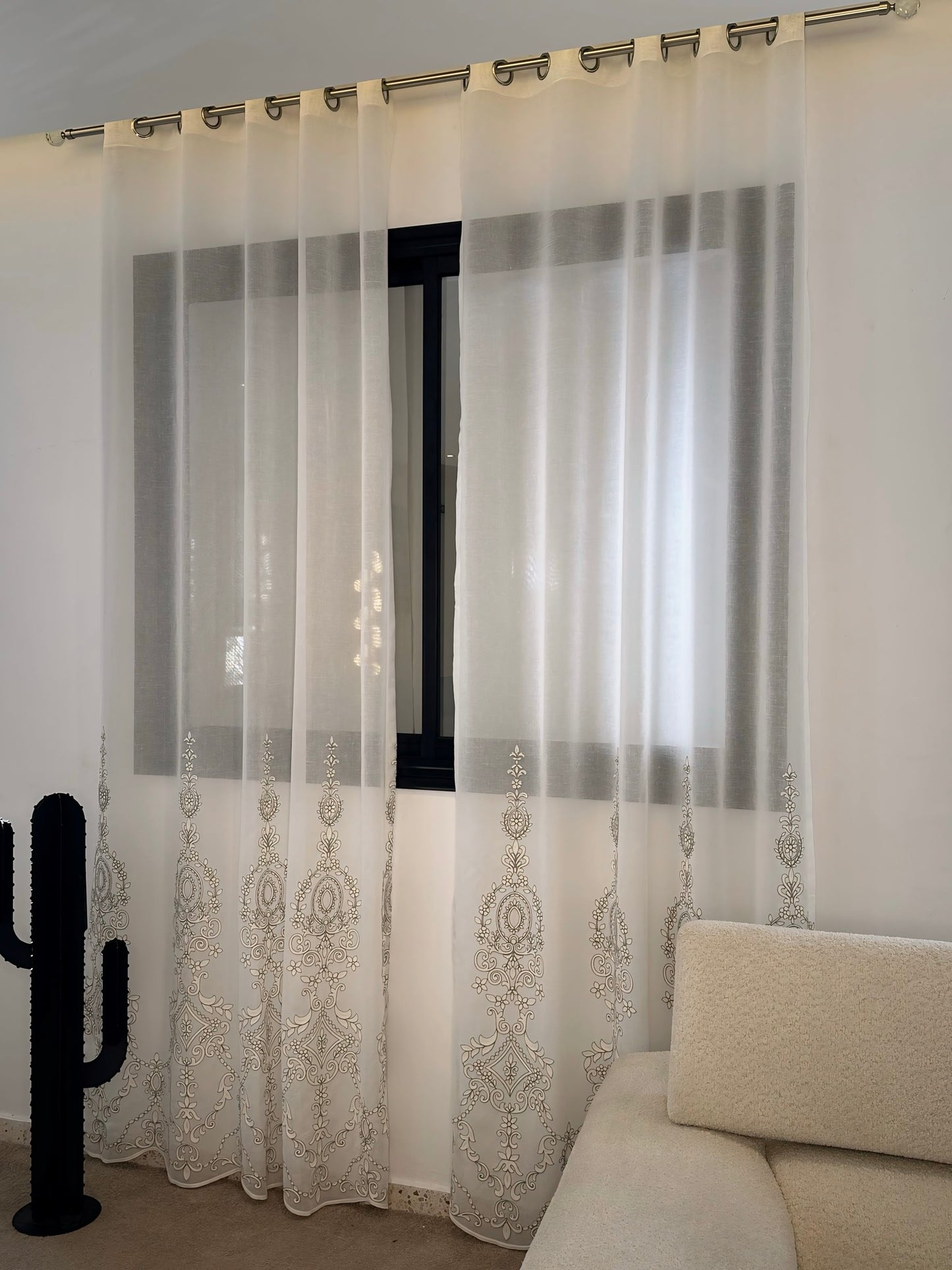 Voile rideau en lin blanc optique tombant devant grande fenêtre dans salon lumineux